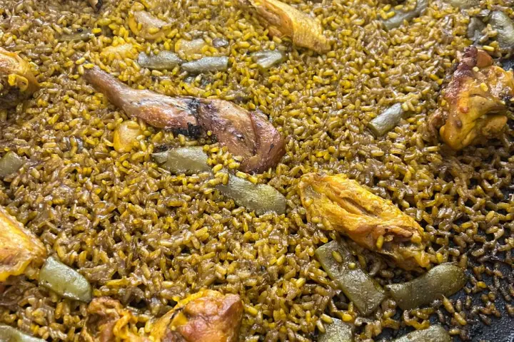 A pan of baked rice with chicken pieces and green beans.